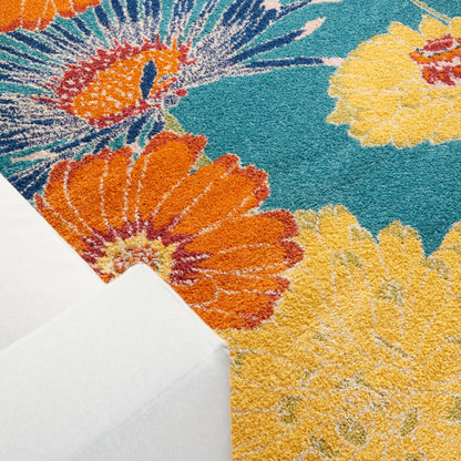 Vibrant floral area rug with orange and yellow blooms on teal background; plush textured pile with white folded corner visible
