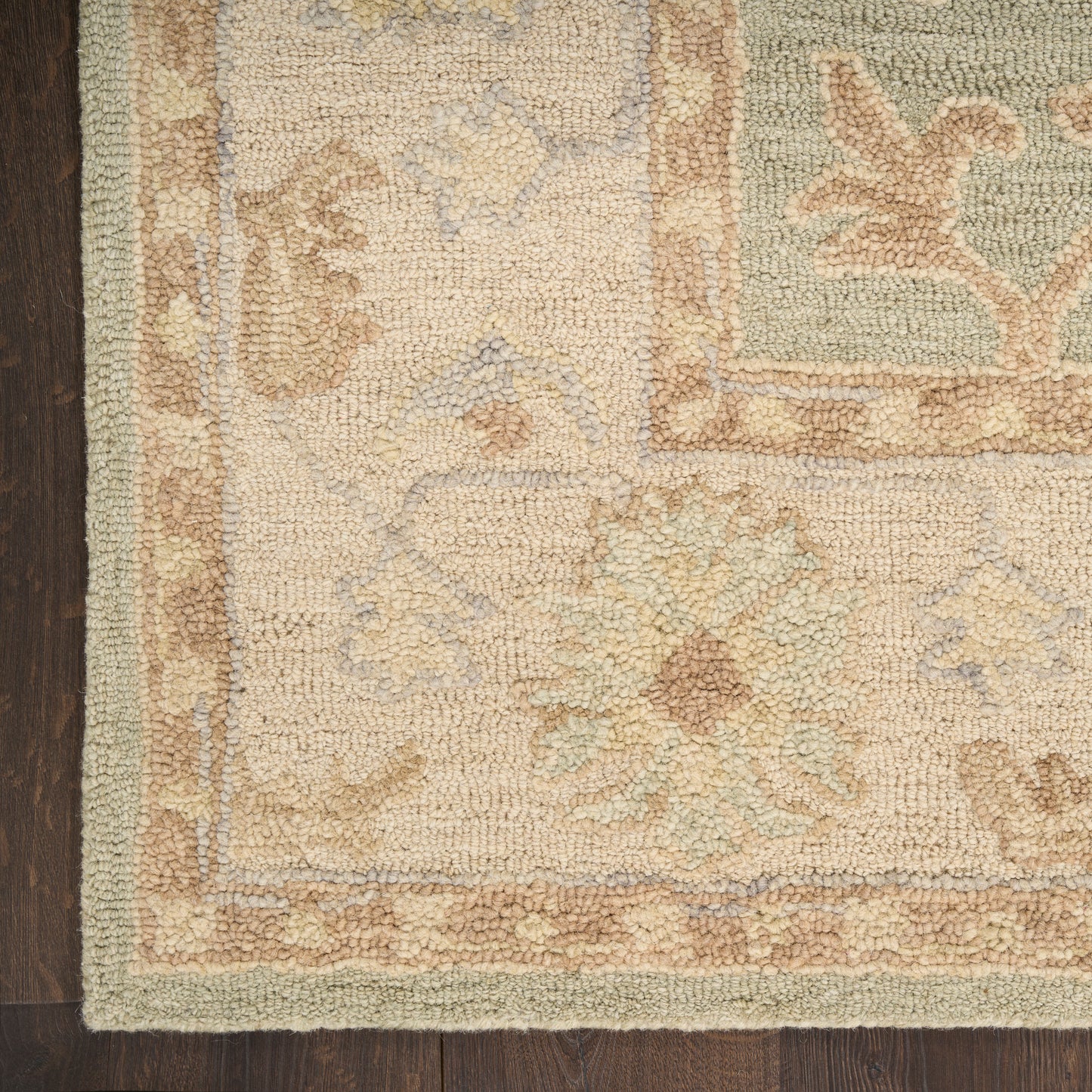 Pastel floral area rug in cream, blue, and tan with beige border on dark wood floor; vintage oriental woven style.