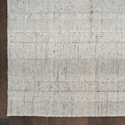 Light gray woven rug with subtle horizontal stripe pattern on dark wood floor