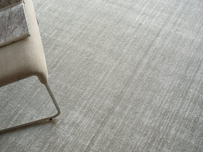 Beige fabric lounge chair with slim metal cantilever frame on light gray textured carpet, modern minimalist style.