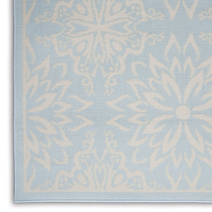 Light blue woven rug with large white snowflake/flower motifs; soft decorative rug with a finished edge
