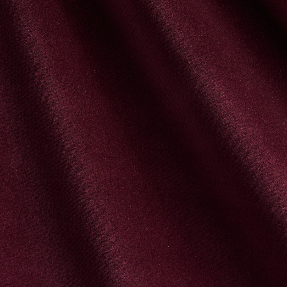Deep burgundy fabric close-up with soft folds and subtle texture.
