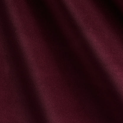 Deep burgundy fabric close-up with soft folds and subtle texture.