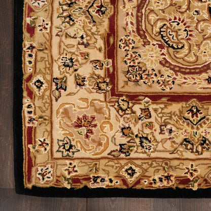 Close-up of an ornate beige oriental rug with gold and red borders and floral motifs on dark wood floor.