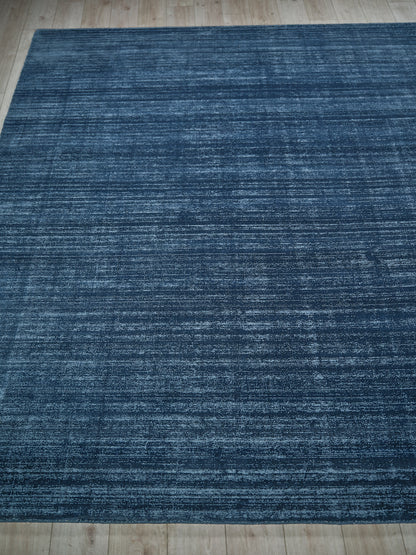 Navy blue rectangular rug with a subtle lighter distressed pattern and woven texture on a wooden floor.