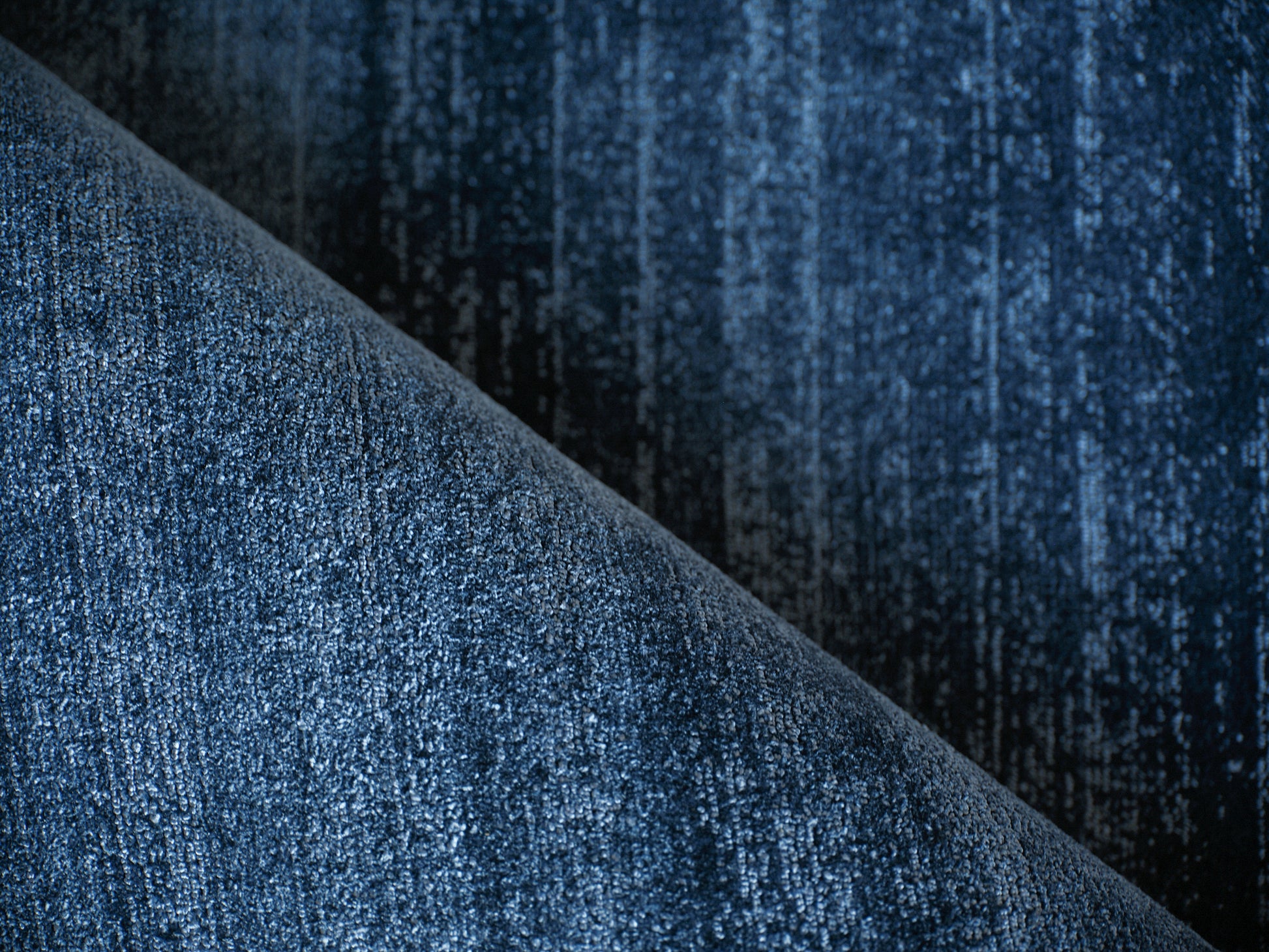 Indigo blue textured rug with a diagonal fold and a rich pile.
