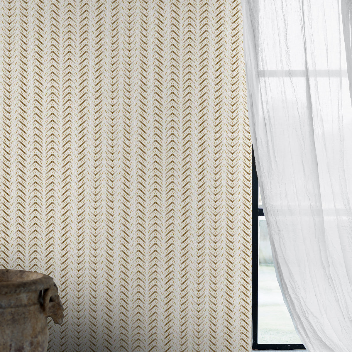 Beige chevron-pattern wallpaper with sheer white curtains beside a black window frame and rustic wooden bowl.