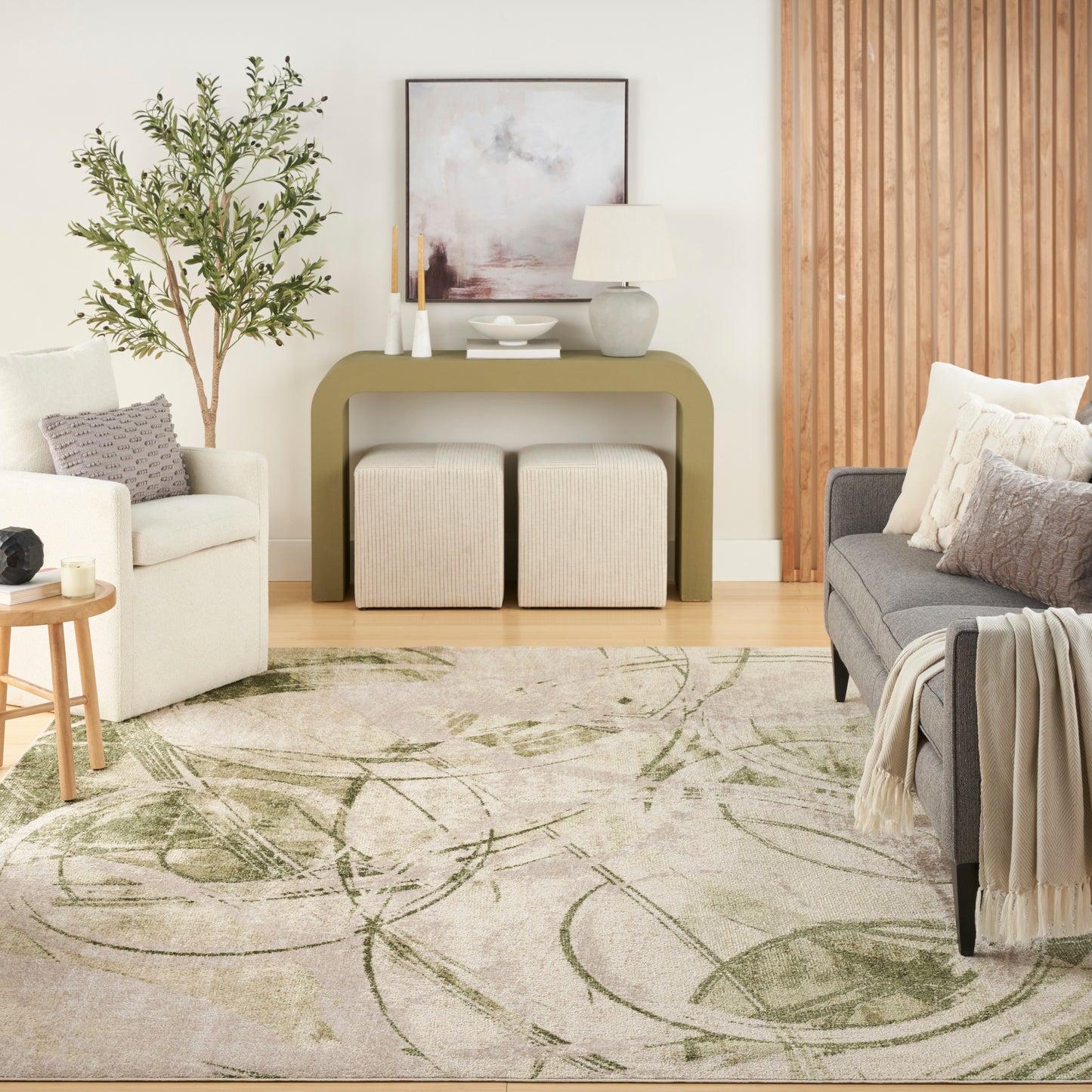 Abstract patterned rug in a contemporary living room, grey tones, with an olive-green console, beige ottomans, grey sofa, a plant and a wood panel wall.