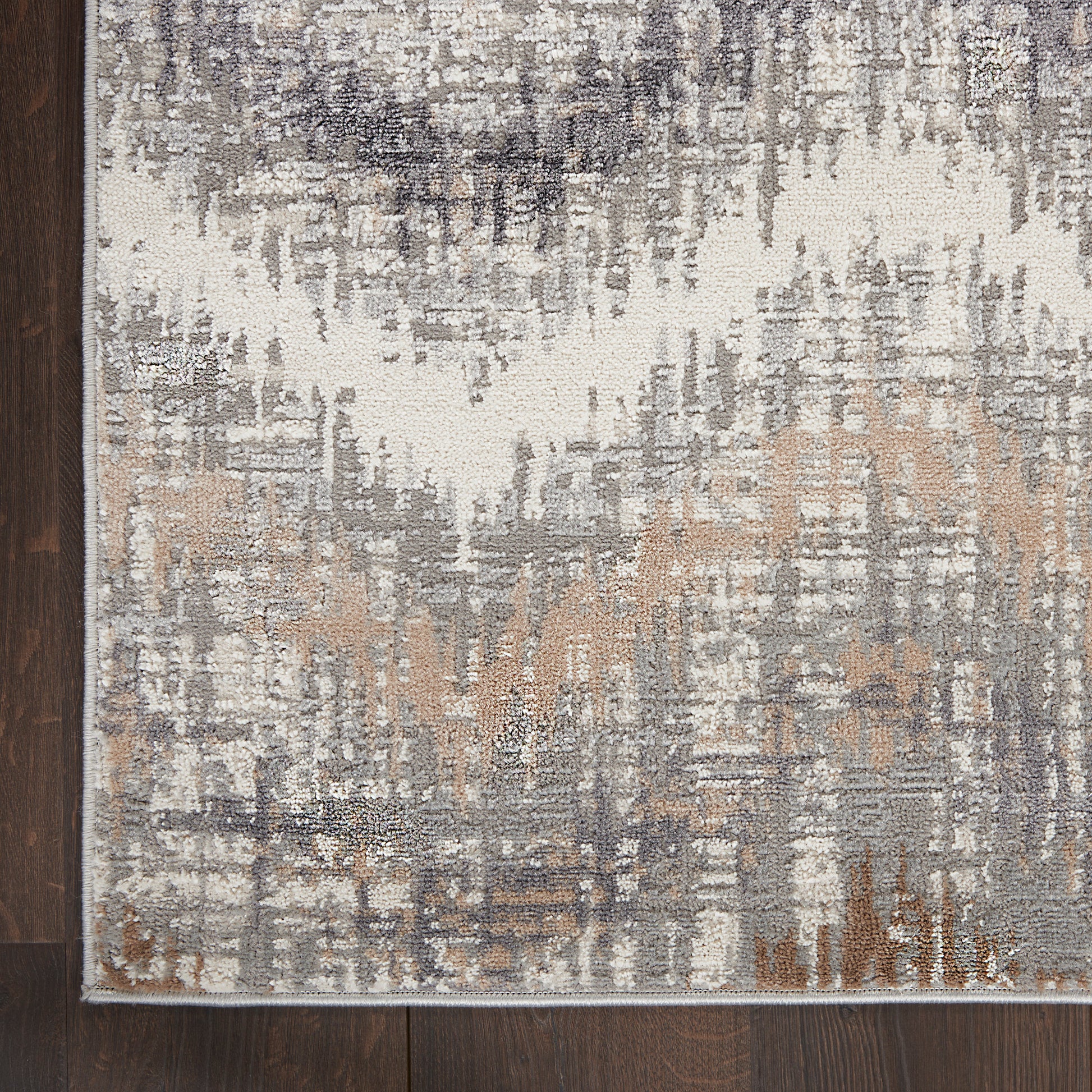 Abstract distressed area rug in ivory, gray, taupe and beige with a light border on dark wood floor.
