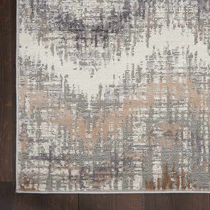 Abstract distressed area rug in ivory, gray, taupe and beige with a light border on dark wood floor.