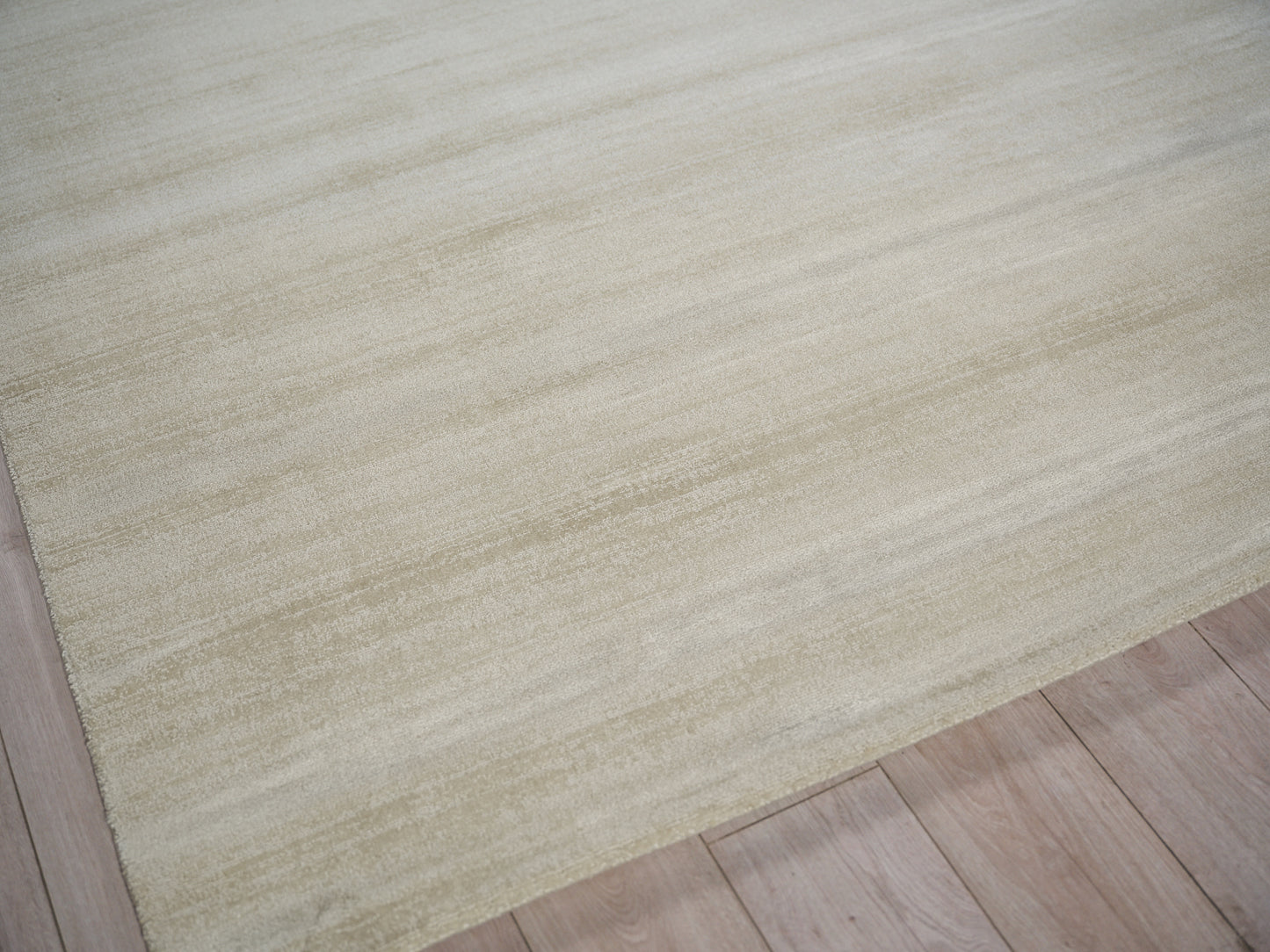 Beige area rug with soft texture and subtle horizontal pattern on light wooden floor.