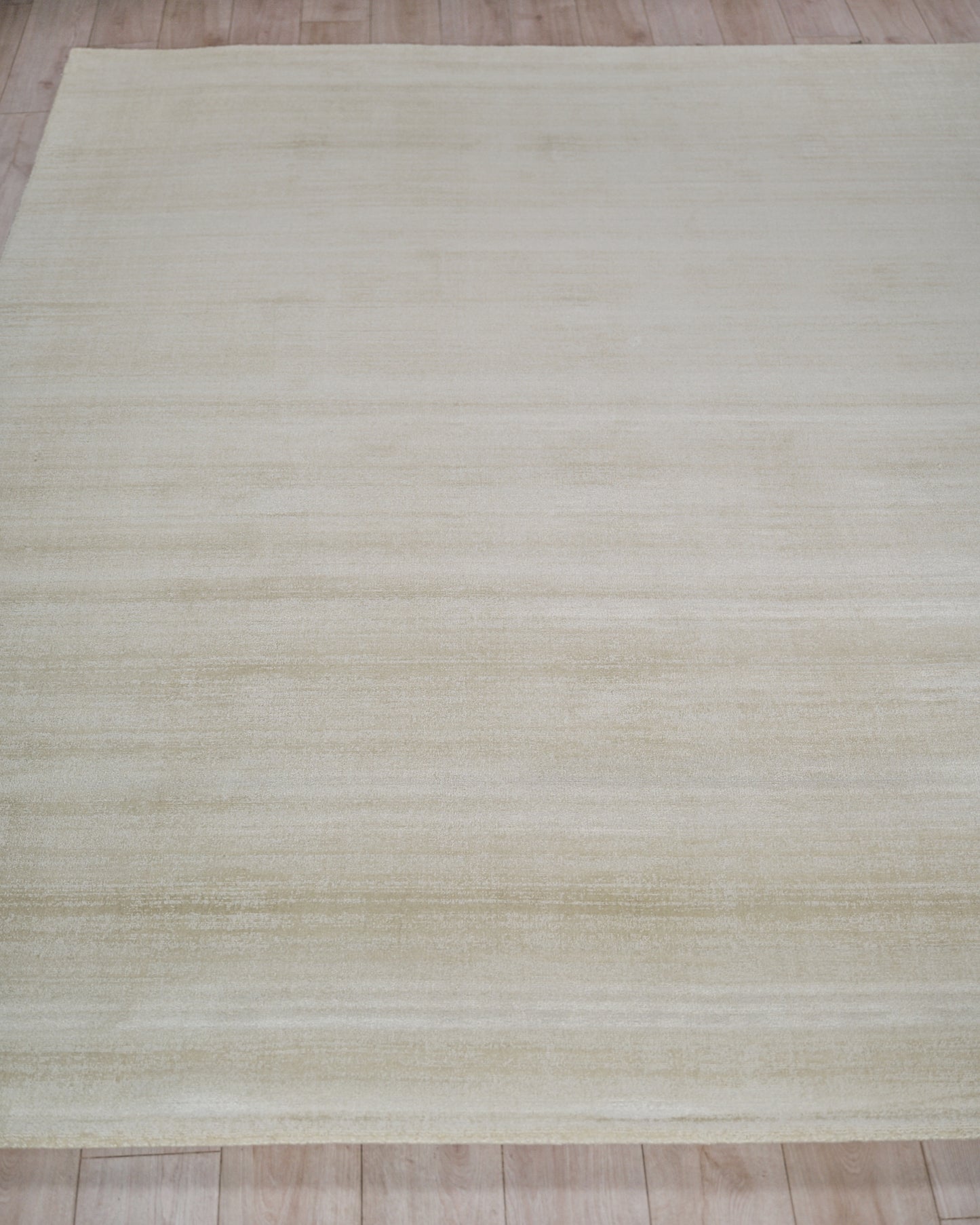 Cream beige rectangular rug with subtle horizontal stripes and soft texture on a light wooden floor.