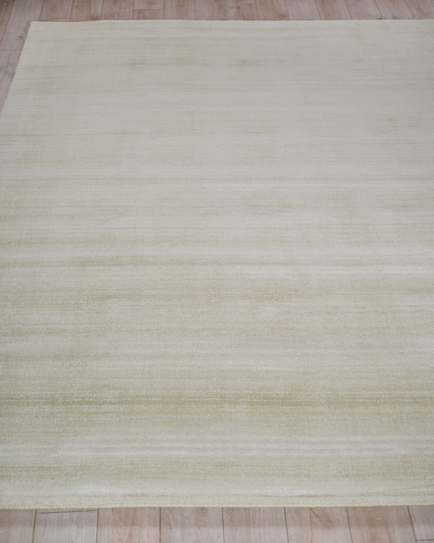 Cream beige rectangular rug with subtle horizontal stripes and soft texture on a light wooden floor.