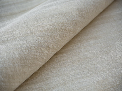 Beige hand-loomed rug with soft nap and subtle sheen, rolled for display; indoor use, 6' x 9'.
