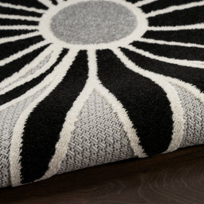 Sunburst rug with black, white and grey radiating stripes; soft textured pile and grey center, on dark wood floor.