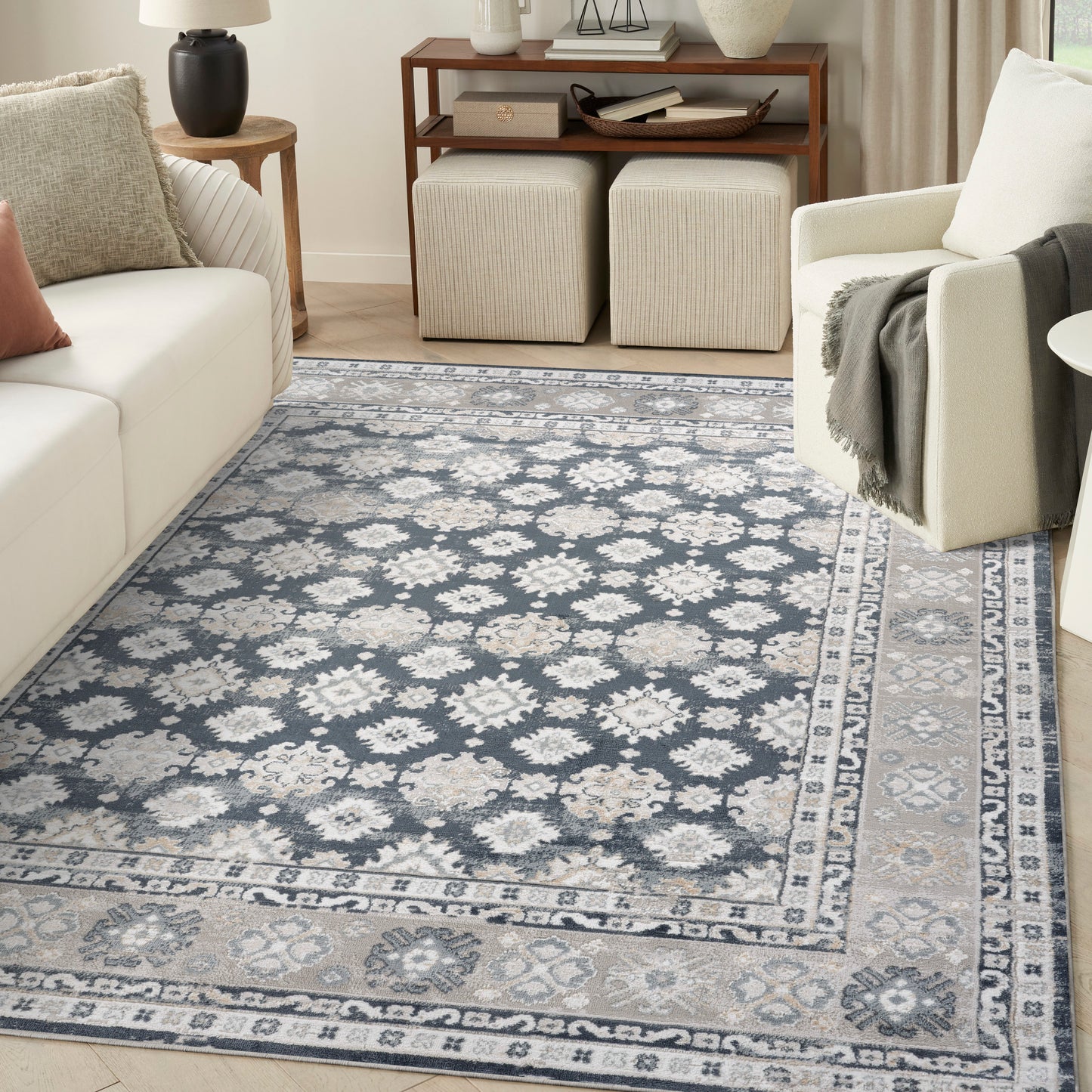 Blue-gray oriental area rug with ivory floral motifs and a light border, laid in a modern living room.