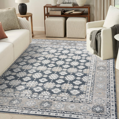 Blue-gray oriental area rug with ivory floral motifs and a light border, laid in a modern living room.