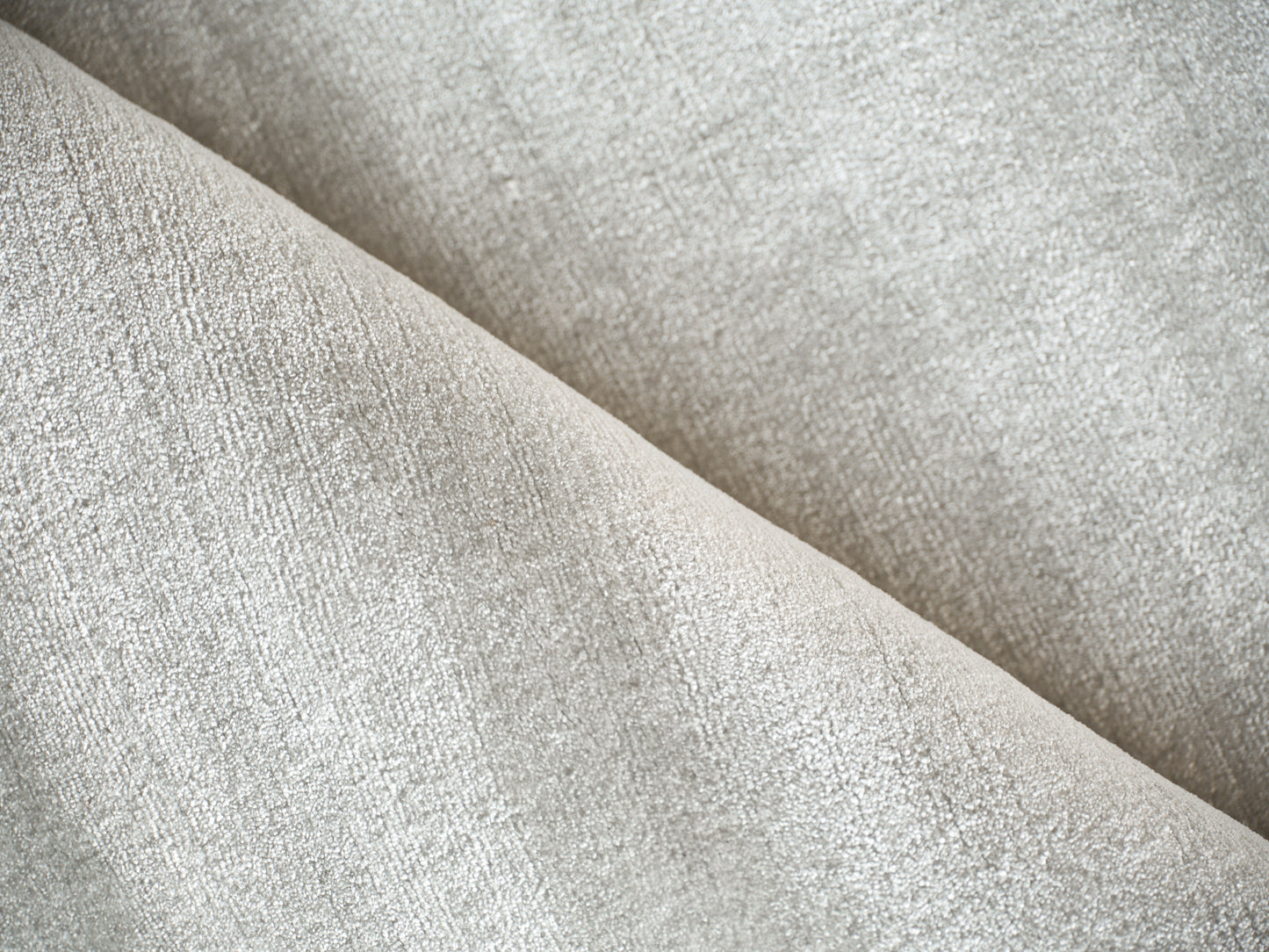 Beige textured upholstery fabric close-up with soft suede-like nap and diagonal folds.