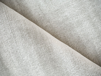Beige textured upholstery fabric close-up with soft suede-like nap and diagonal folds.