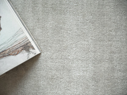 Corner view of a glossy magazine with a seaside image, resting on a light gray textured surface.
