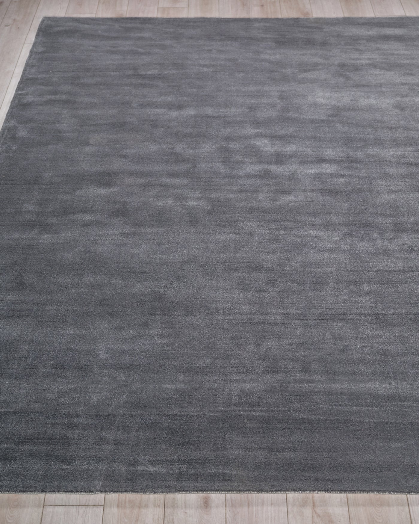 Charcoal gray rectangular rug with subtle tonal texture on light wood floor; modern minimalist, low-pile.