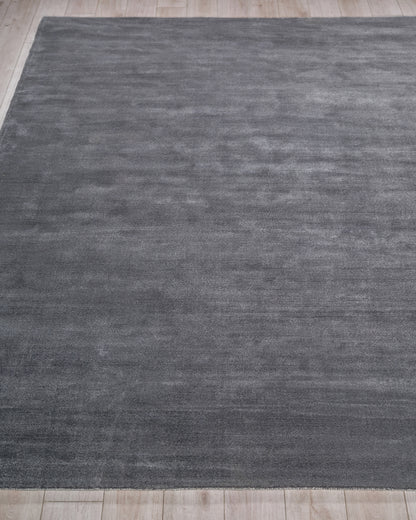 Charcoal gray rectangular rug with subtle tonal texture on light wood floor; modern minimalist, low-pile.