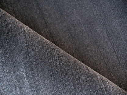 Dark grey rug close-up showing weave, diagonal fold and soft texture.
