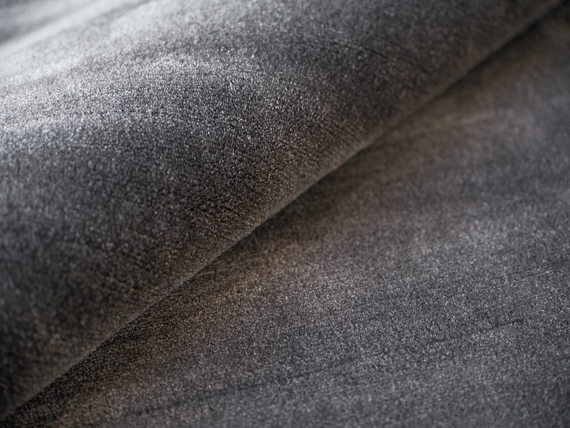 Dark charcoal gray rug close-up with soft nap and folds.