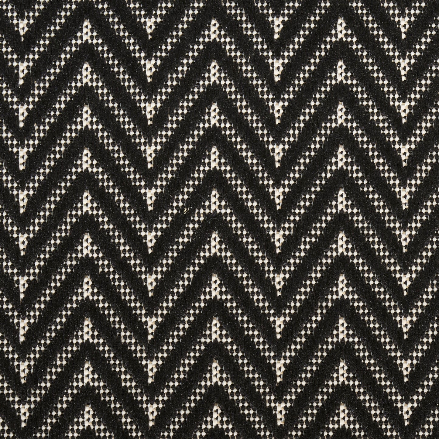 Black rug with a white chevron zigzag beaded pattern and a textured geometric weave (3' x 5').
