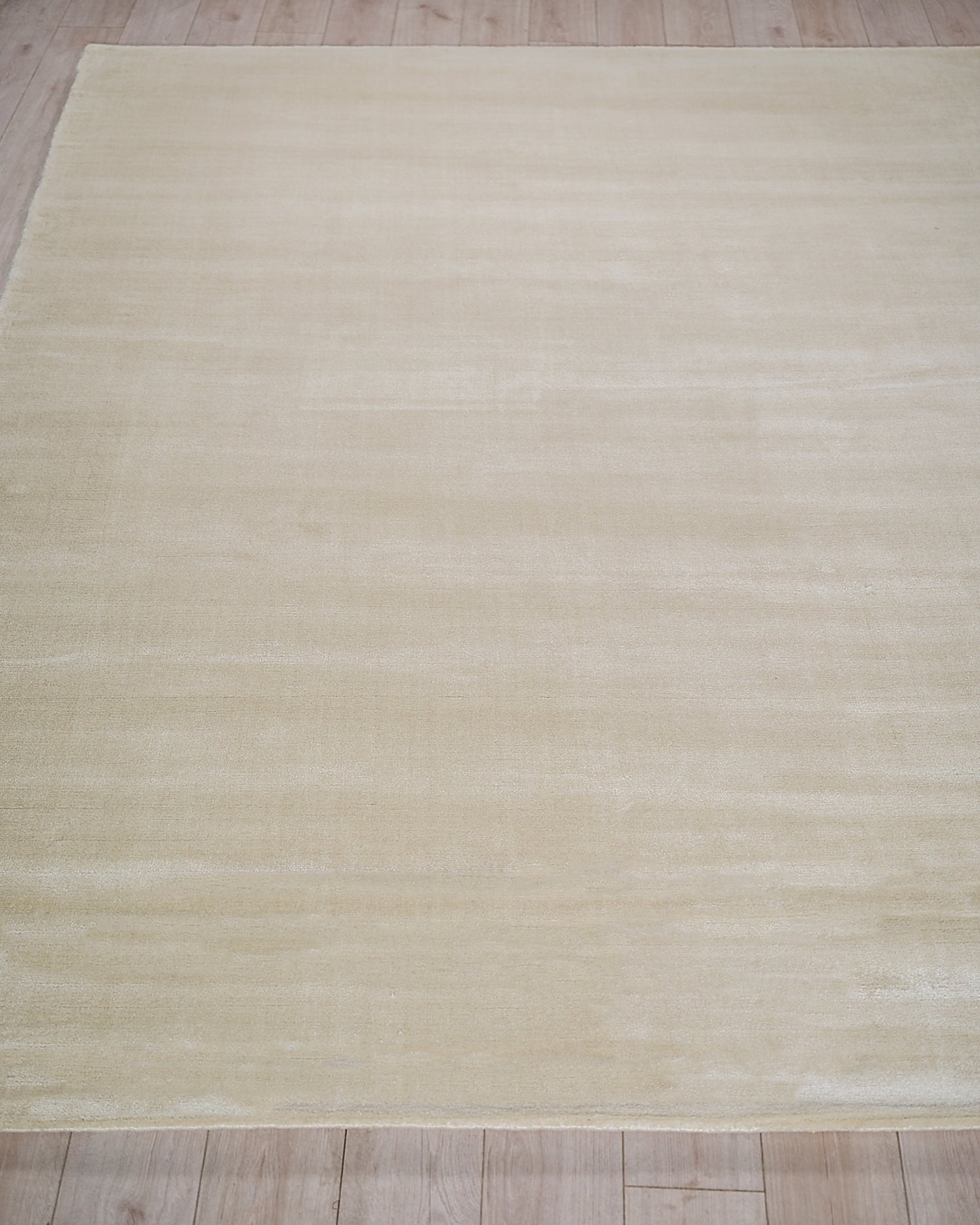 Cream-beige rectangular rug with subtle tonal stripes on a light wood floor.