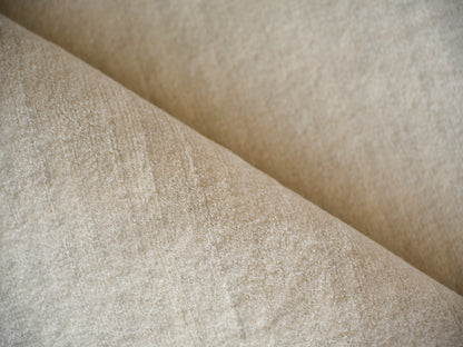 Beige rug with a soft, shimmering texture and a diagonal fold; hand-loomed indoor rug.