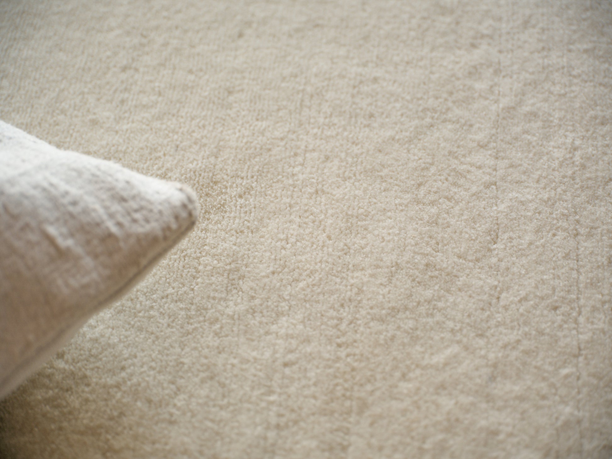 Cream rug with a soft woven texture on a beige background; minimalist, cozy home decor.