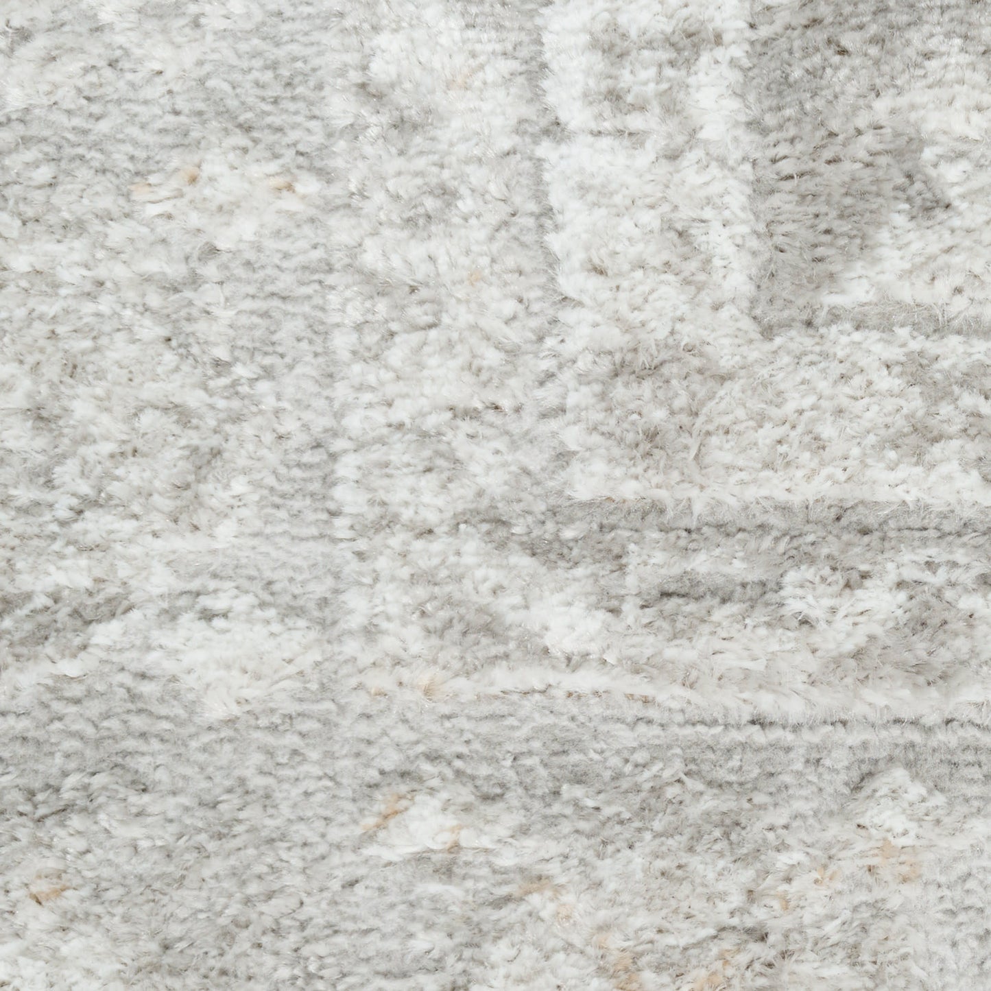 Close-up view of a plush shag rug in cool gray and ivory tones with a soft, high-pile texture.