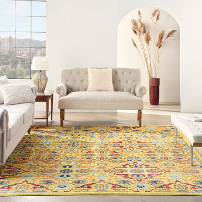 Living room with a beige tufted sofa on wooden legs, a light gray sofa, side-table lamp, and a colorful yellow-blue-red Persian rug, pampas grass vase by an arch alcove.