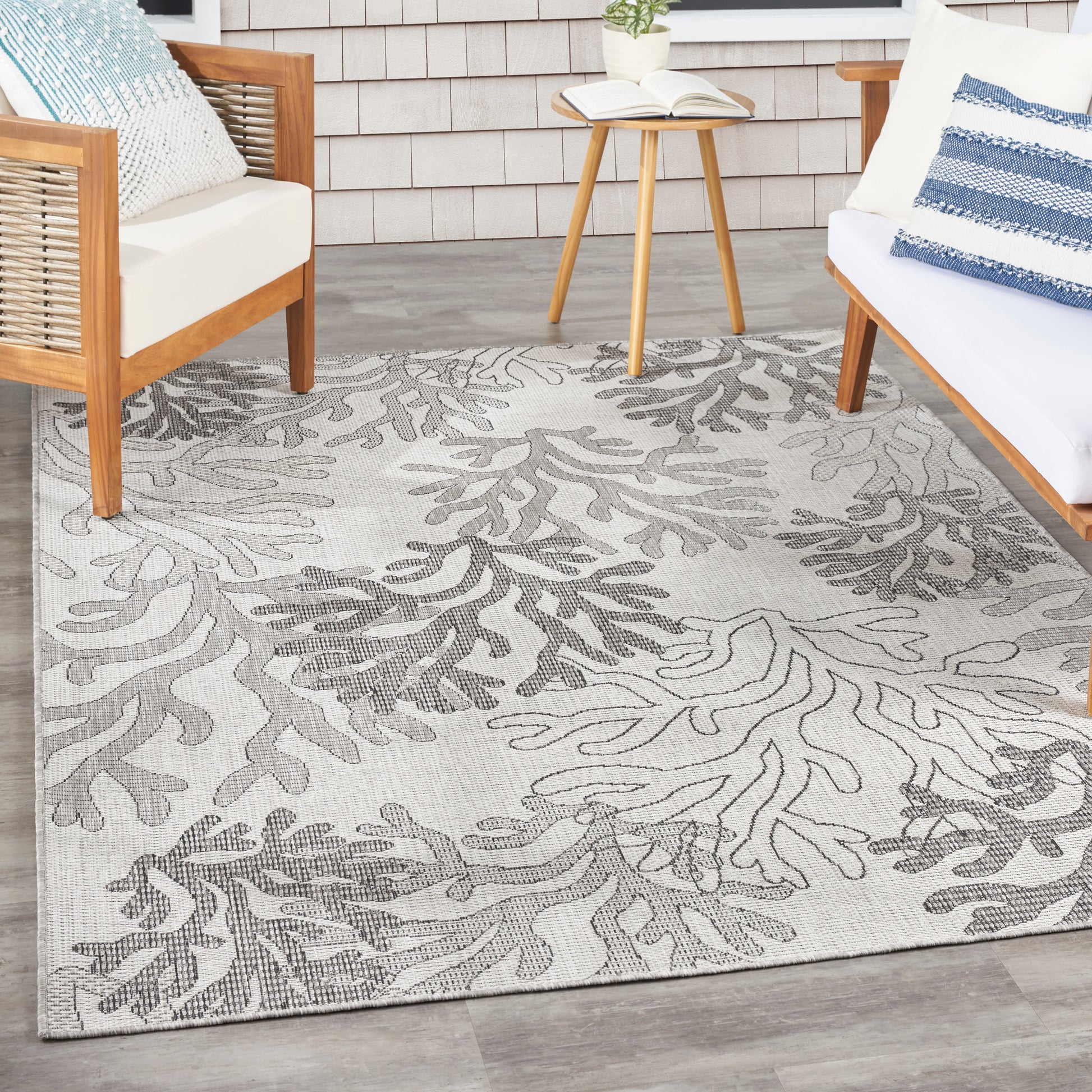 Beige area rug with gray botanical leaf pattern and woven texture for a modern coastal living room.