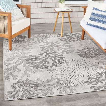 Beige area rug with gray botanical leaf pattern and woven texture for a modern coastal living room.