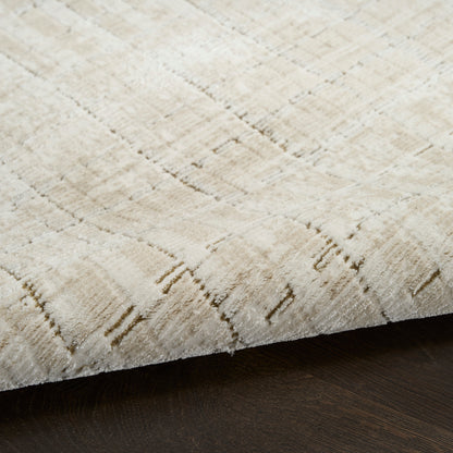 Beige area rug with subtle linear pattern and soft texture, edge resting on dark wooden floor.