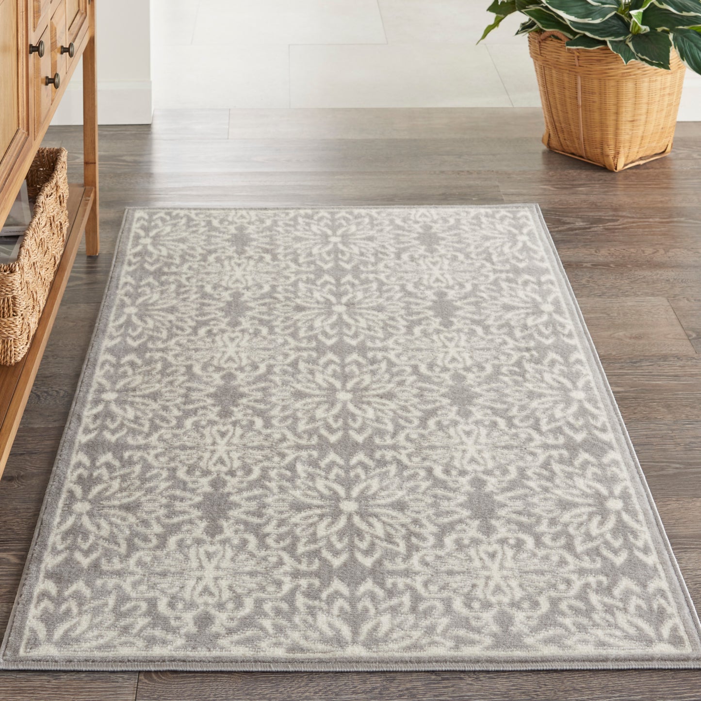 Gray and ivory damask-patterned area rug on dark hardwood floor; rectangular, cozy, classic-modern style.