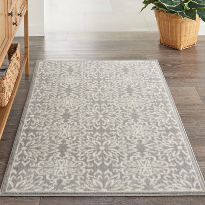 Gray and ivory damask-patterned area rug on dark hardwood floor; rectangular, cozy, classic-modern style.