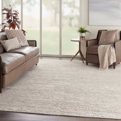 Beige textured area rug in a living room with brown leather sofas, neutral pillows, a cozy throw, and a plant on a small side table.