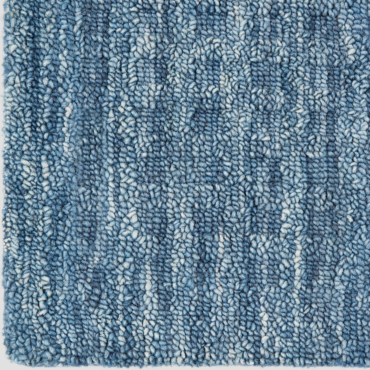 Blue textured shag rug with dense looped pile and subtle white flecks; cozy, modern Berber-inspired style.