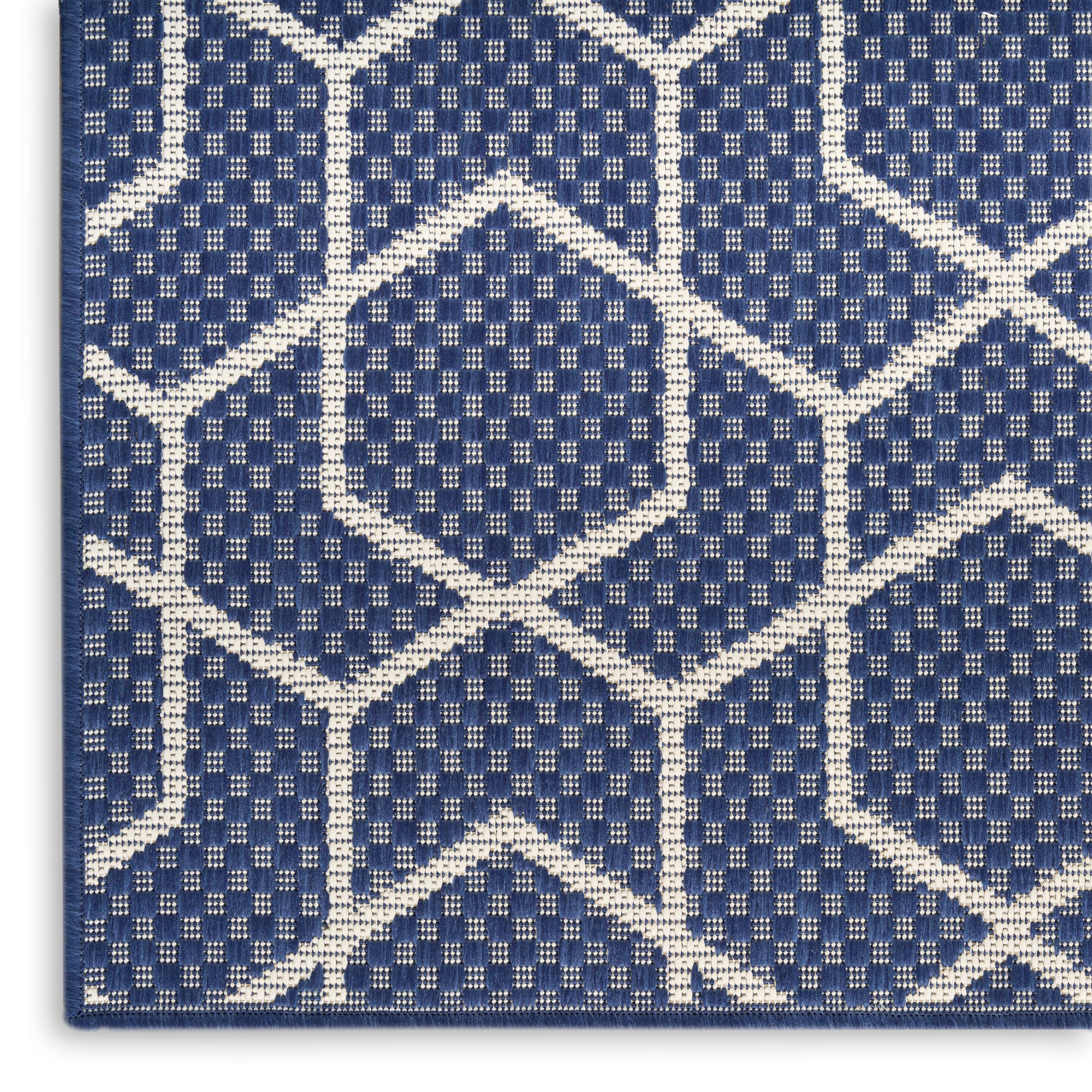 Close-up of navy blue woven rug with white geometric lattice pattern.