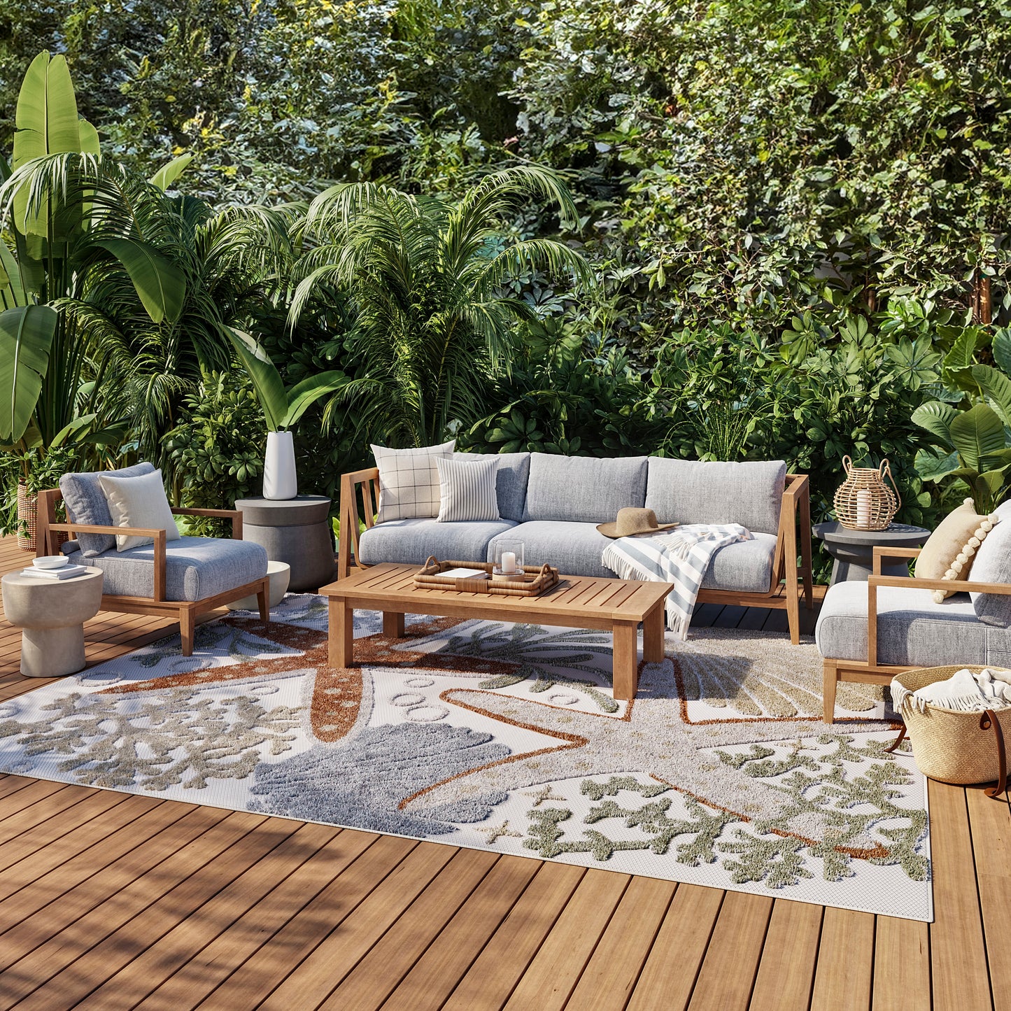 Leaf-pattern outdoor rug on a wooden deck amid lush tropical plants; 9' x 12'.