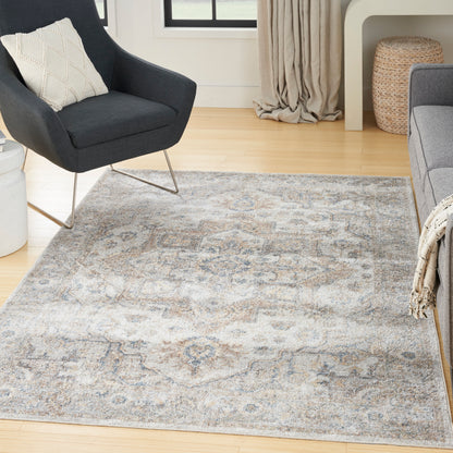Dark gray mid-century armchair with metal legs beside a blue-gray oriental patterned area rug in a bright living room.