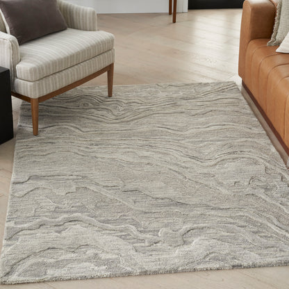 Light gray textured area rug with swirling wave pattern between beige fabric sofa and tan leather sofa.