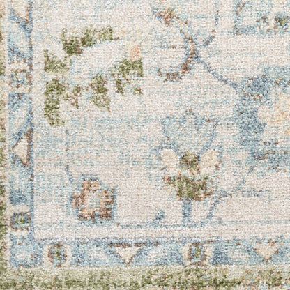 Pastel cream textured rug with pale blue border and green floral motifs; vintage-inspired, tufted pile.