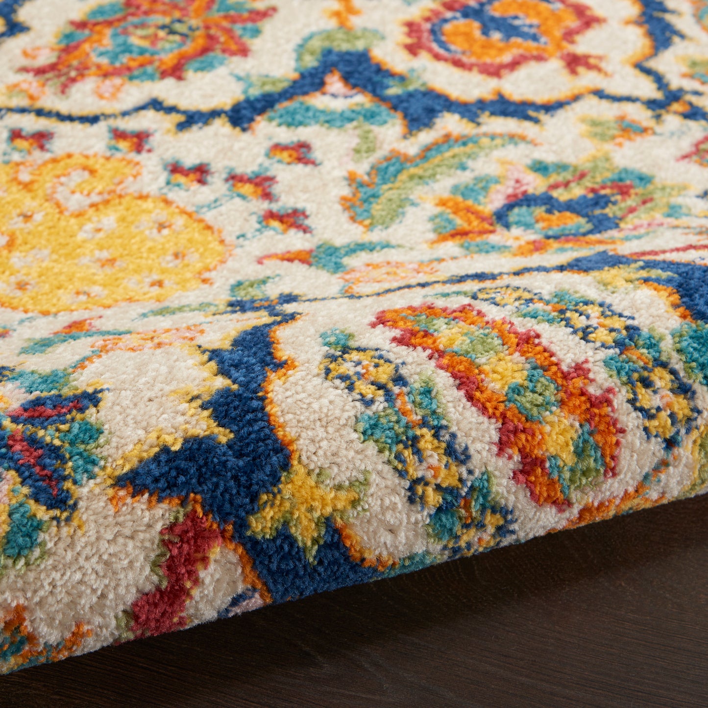 Close-up of a vibrant multicolor rug with thick plush pile; blue, yellow, orange and green floral patterns.