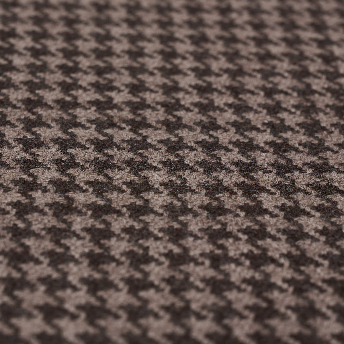 Close-up of brown and beige houndstooth wool fabric with textured weave, ideal for suits and coats.