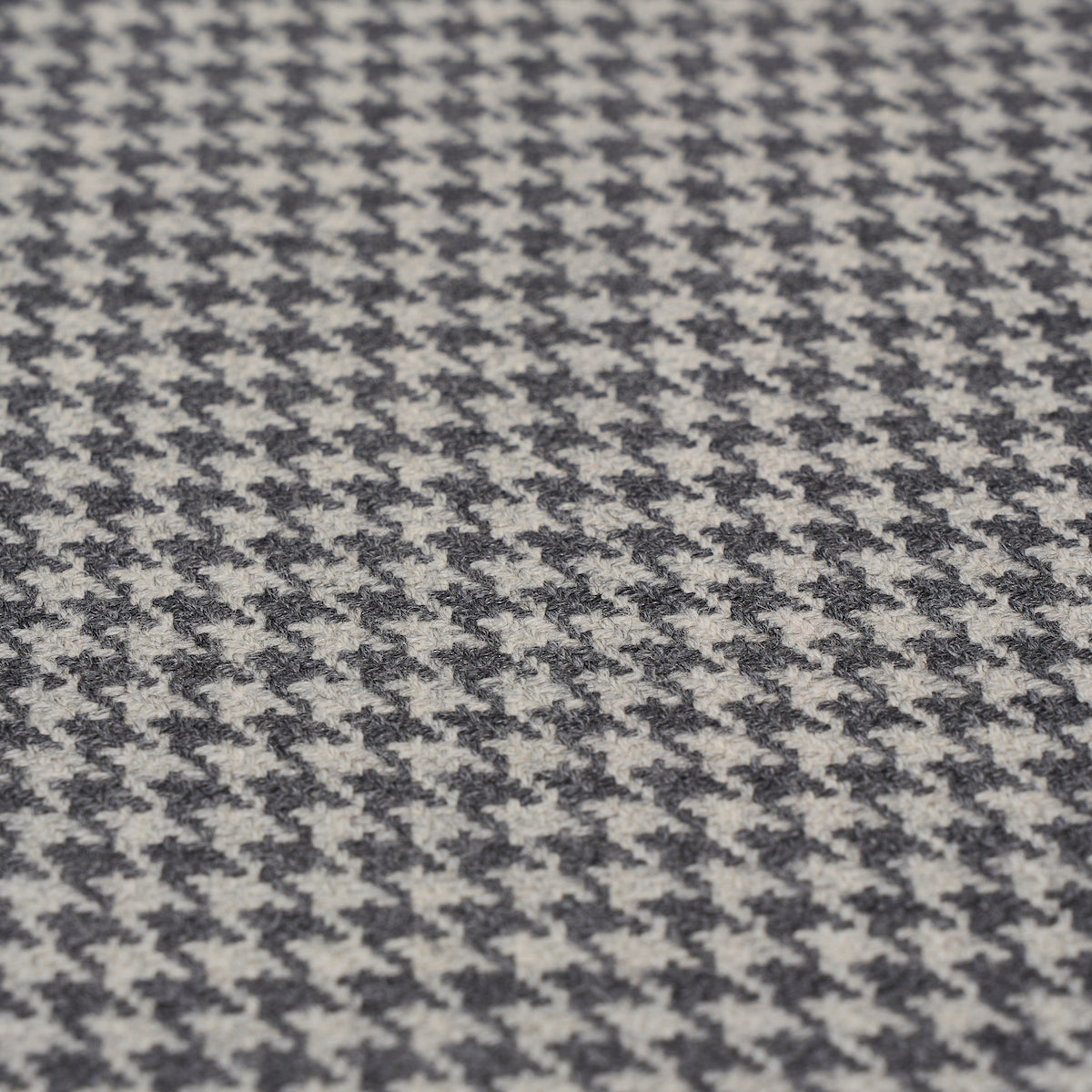 Close-up of black and white houndstooth wool fabric texture, oxford grey suiting material.