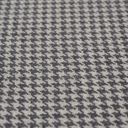 Close-up of black and white houndstooth wool fabric texture, oxford grey suiting material.